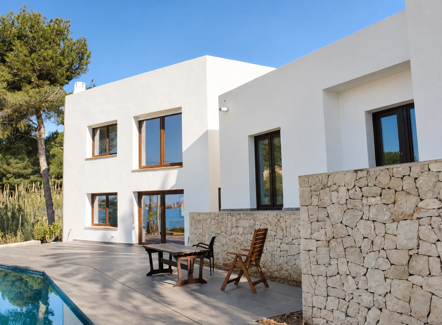 Façade blanche et murs en pierre de la maison à Cala Baladrar